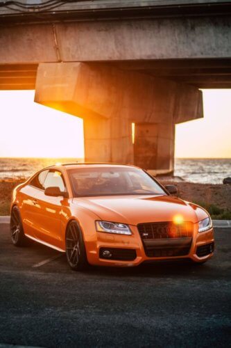 orange sports car parked near water