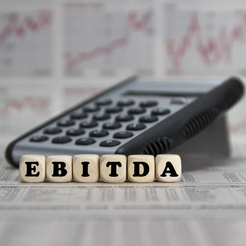 EBITDA word built with letter cubes on newspaper background