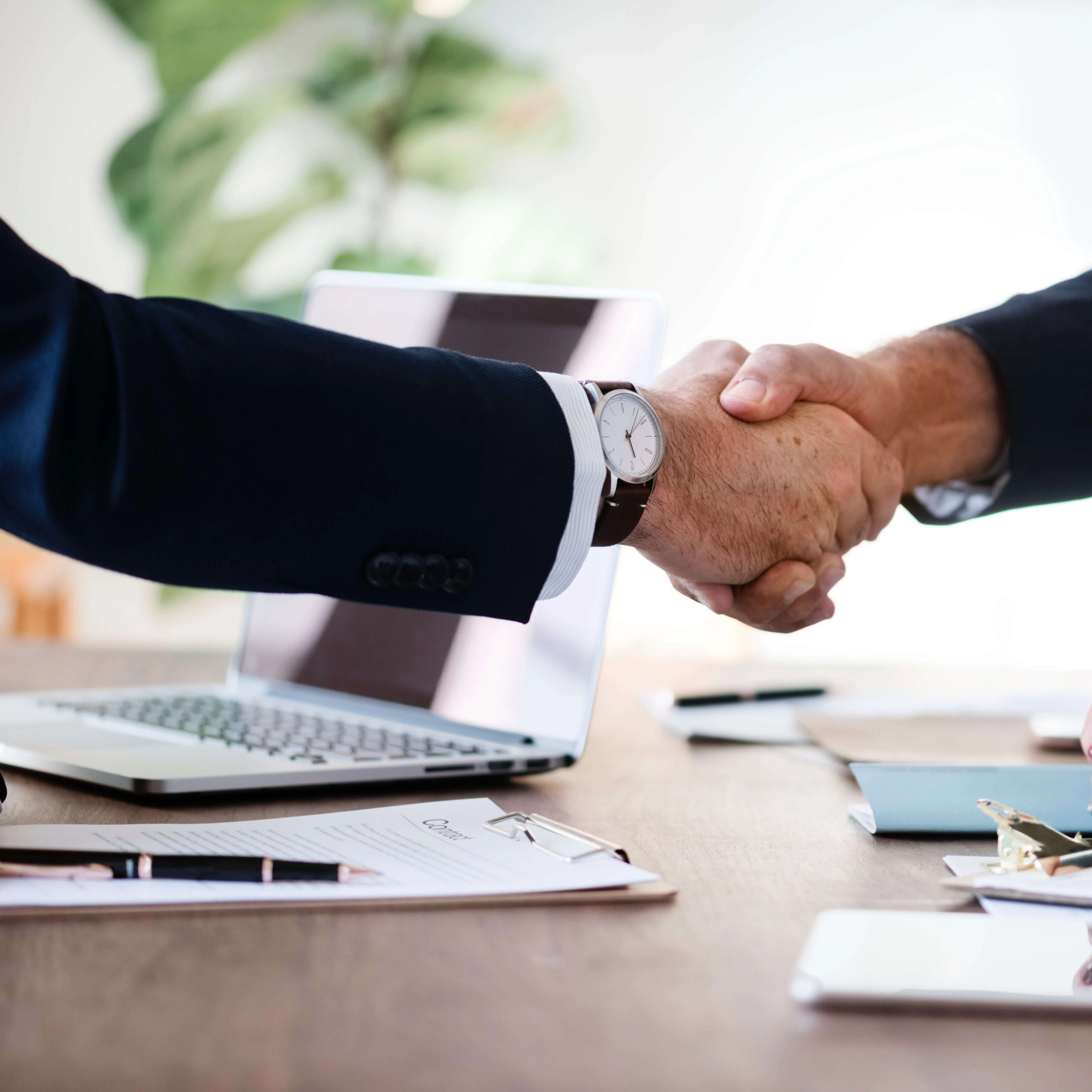 Two men shaking hands over a table with paper